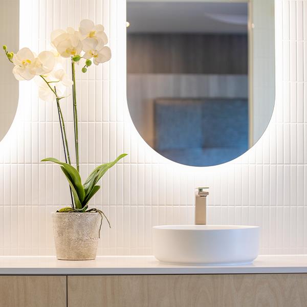 bathroom sink with curved oval backlit mirror